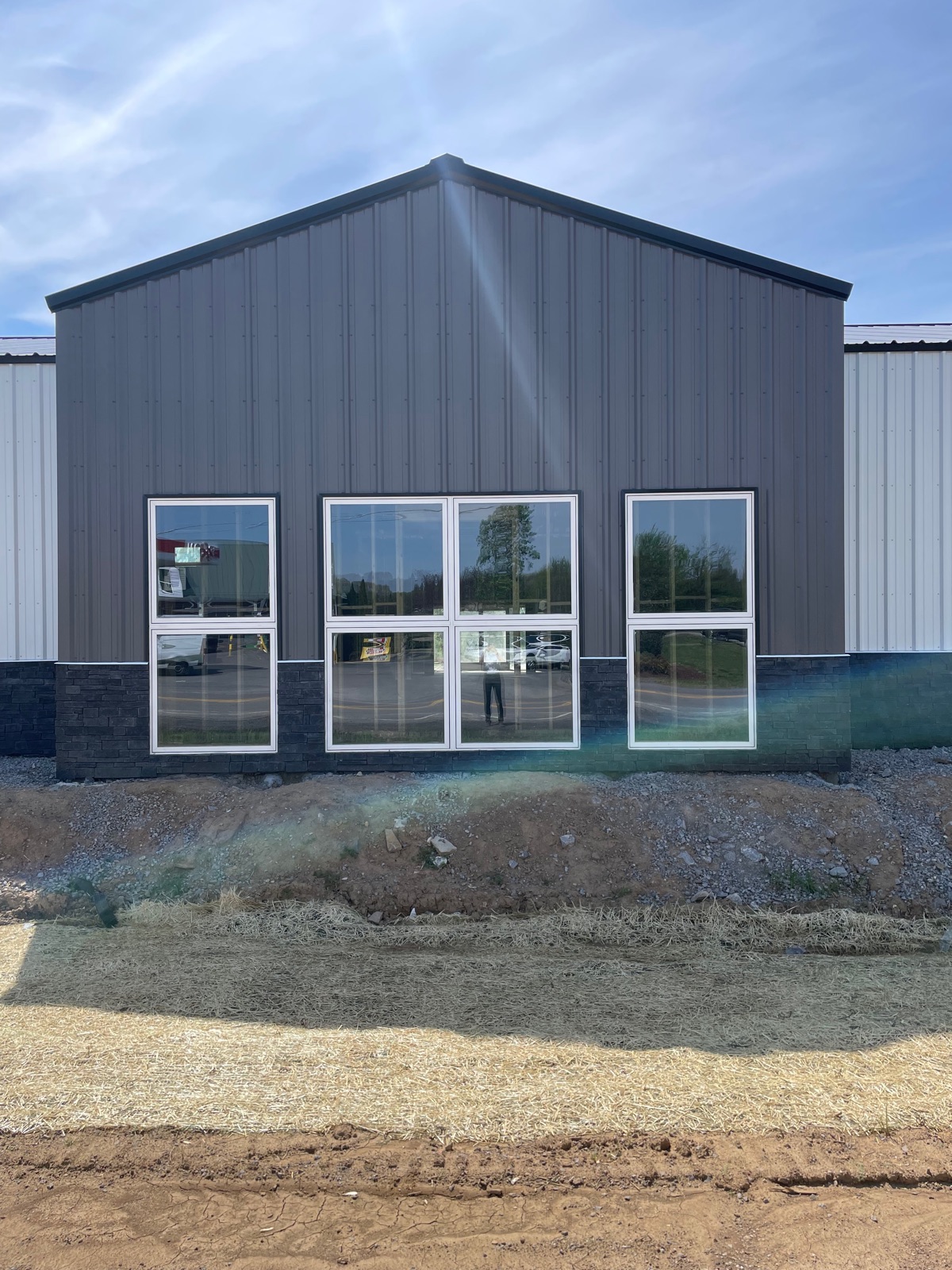 Front gable of Thompson's Station Hardware featuring large showroom windows that reflect the sky, with stone accent wainscot below.