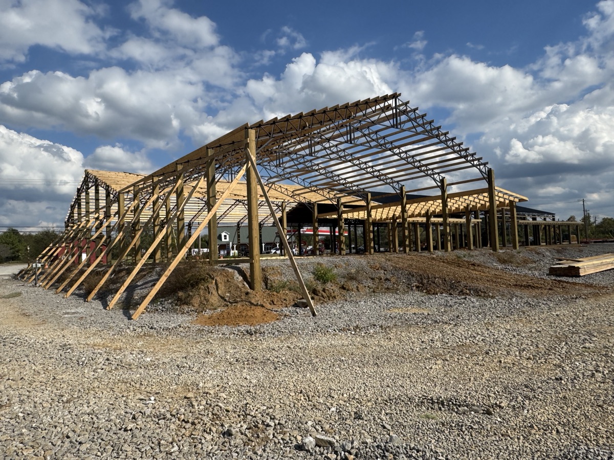 Detailed exterior shot of Thompsons Station Hardware construction in Franklin, TN, focusing on the roof structure with black panels and exposed wooden framing against a clear sky.