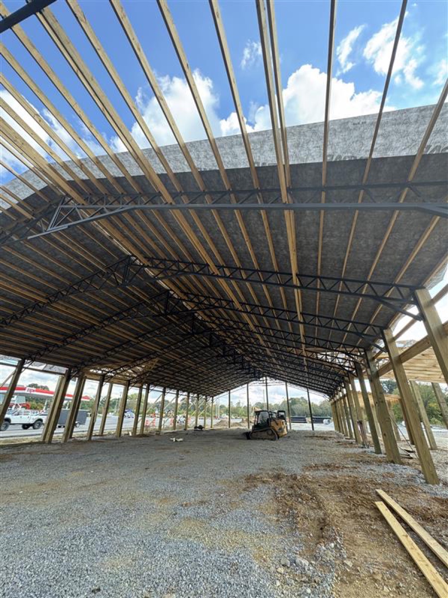 Exterior shot of Thompsons Station Hardware construction in Franklin, TN, highlighting the progress on the roof installation with black roofing material over wooden framing.
