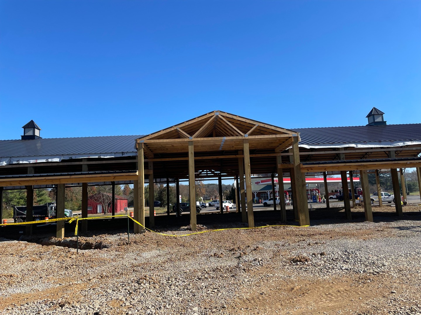 Front view of Thompson's Station Hardware construction in Franklin, TN, featuring the main entrance gable framing with cupolas on the completed metal roof behind it.